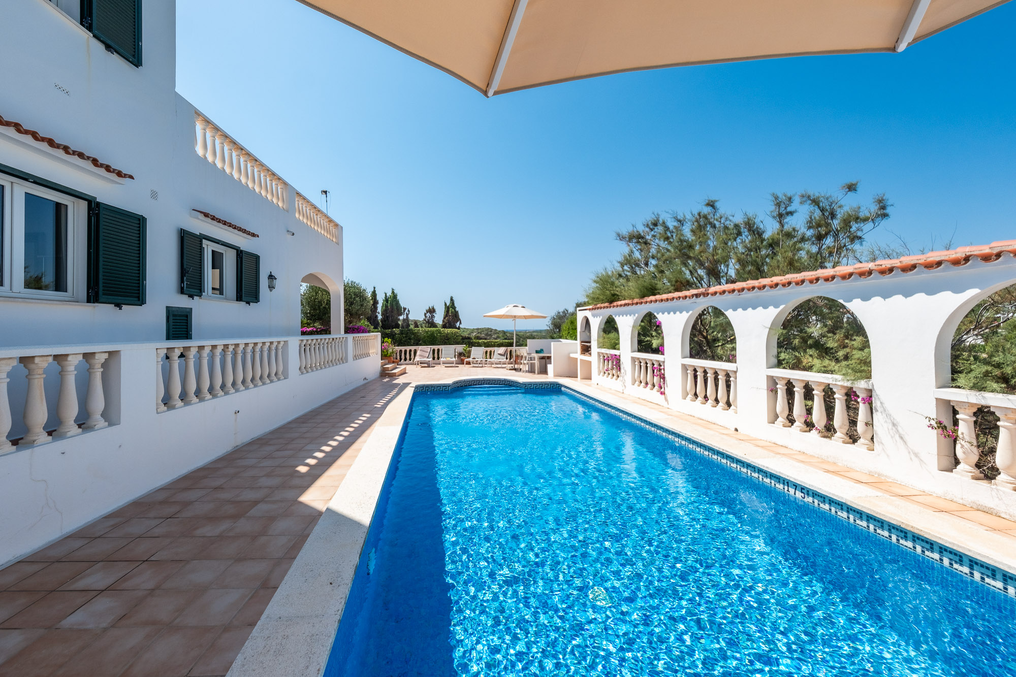 Villa surélevée à Cala Llonga avec vue sur la mer et le port de Mahón, et une grande terrasse avec piscine.